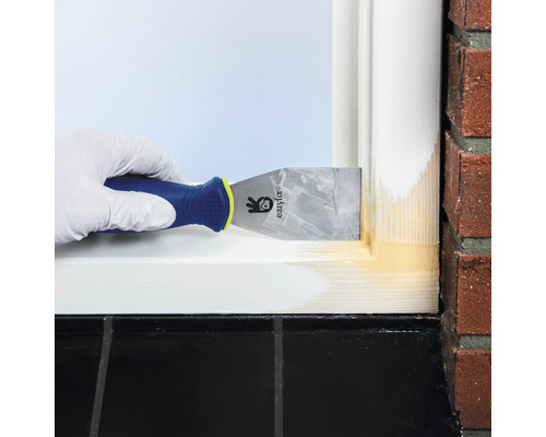 Een persoon gebruikt een plamuurmes om voegmiddel op een raamkozijn aan te brengen.