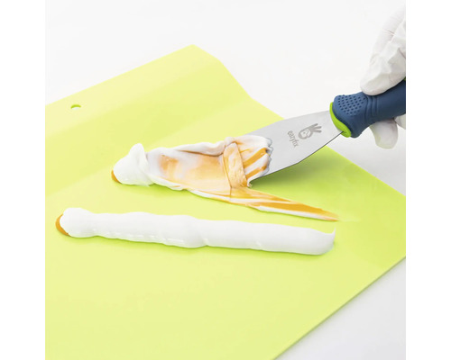 Plamuurmes met witte en bruine massa op een ondergrond