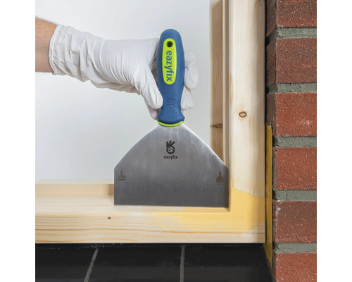 Hand met plamuurmes bij het voegen van een houten frame