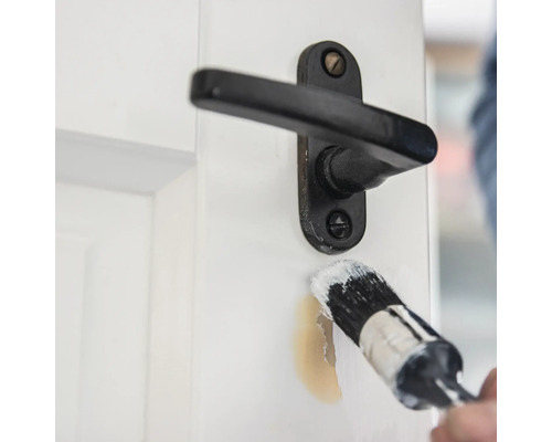 Schilderen van een deur met een kwast in de buurt van een deurklink