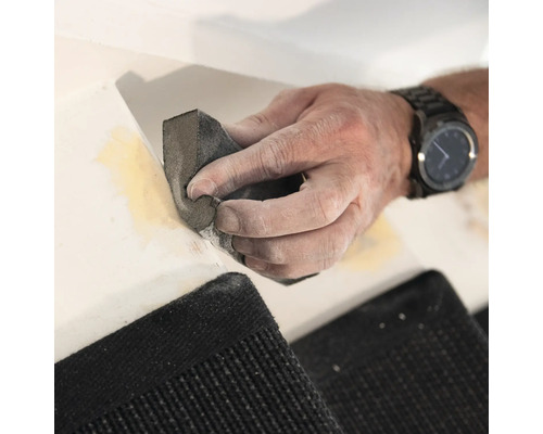 Hand schuurt vulmiddel op een oppervlak