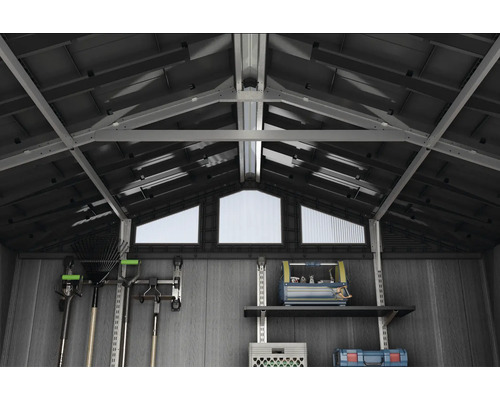 Binnenaanzicht van een tuinhuis met dakramen, planken en gereedschapshouders voor opslag