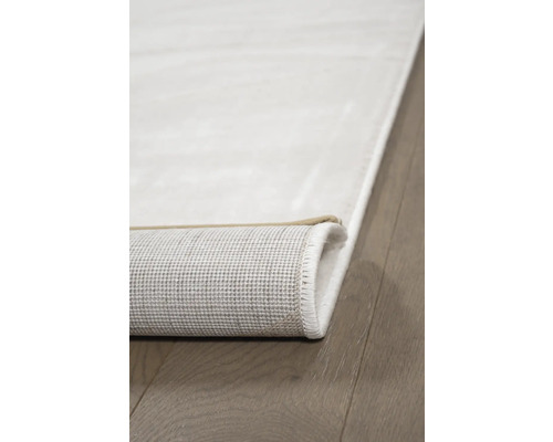 Detailopname van een lichtgekleurd tapijt met opgerolde rand