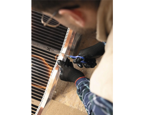 Een persoon knipt een vloerverwarmingsmat met een schaar.