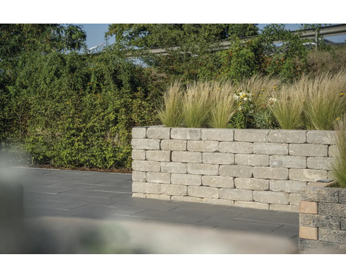 Tuinmuur van steen met beplanting voor een georganiseerde buitenruimte.
