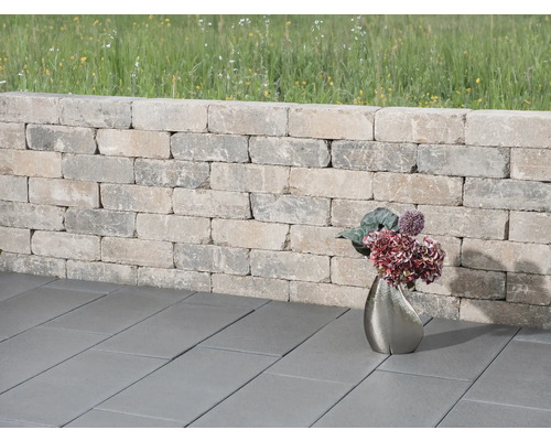 Tuinmuur van stenen met straatstenen en bloemenvaas