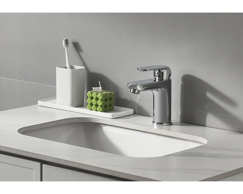 Badkamer wastafel met kraan, tandenborstelbeker en decoratieve kaars.