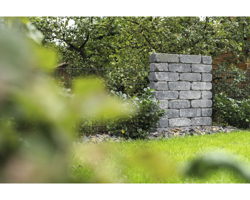 Gemetselde tuinkolom van stenen blokken naast een gazon