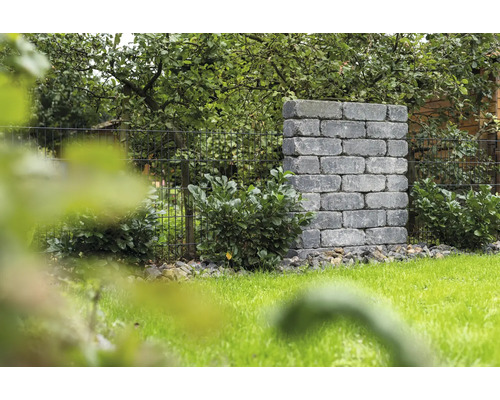 Landschapsbeeld met metselwerk van stenen blokken en metalen hek in de tuin