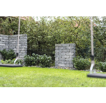 Tuin met gazon, beplante stenen muren en schommel