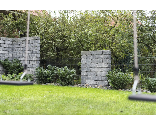 Tuin met gazon, beplante stenen muren en schommel