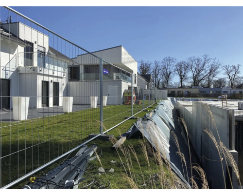 Bouwplaats met bouwschutting en ruwbouw van een huis