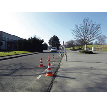Scene met verkeerskegels en een waterpasinstrument op een weg voor verkeersbegeleiding.