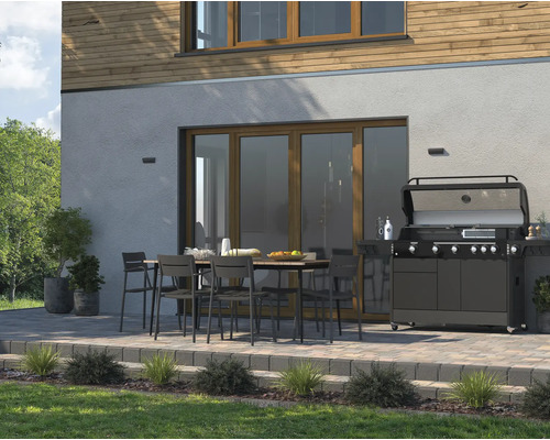 Terras met eettafel, stoelen en gasbarbecue voor een woonhuis.