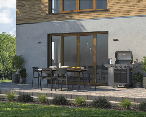 Terras met tuintafel, stoelen en barbecue voor een huis.