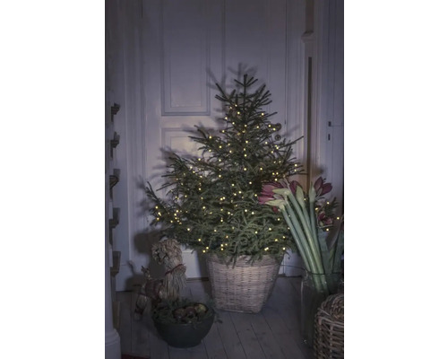 Kerstboom met lichtjes in een mand in een kamer