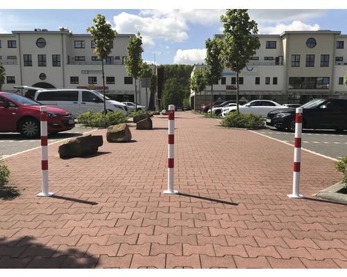 Drie rood-wit gestreepte afzetpalen op straatstenen