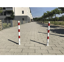 Twee rood-wit gestreepte verkeerspalen op een betegeld pad.