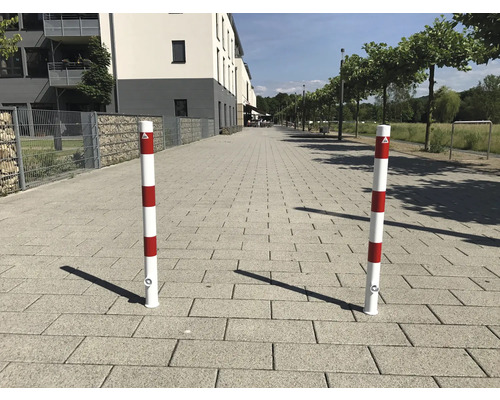 Twee rood-wit gestreepte verkeerspalen op een betegeld pad.