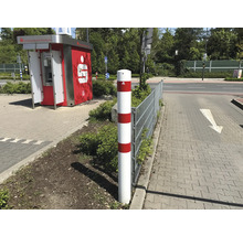 Witte verkeerspaal met rode strepen naast een trottoir