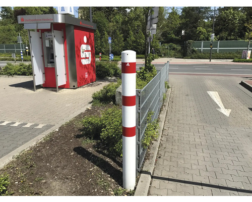 Witte verkeerspaal met rode strepen naast een trottoir