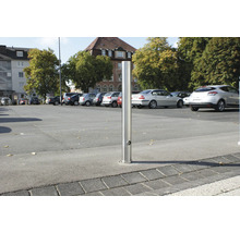 Roestvrijstalen bolder op een parkeerplaats met geparkeerde auto''s.
