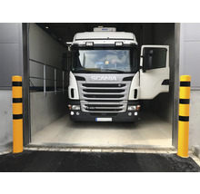 Een vrachtwagen rijdt een magazijn binnen, geflankeerd door aanrijbeveiligingspalen.