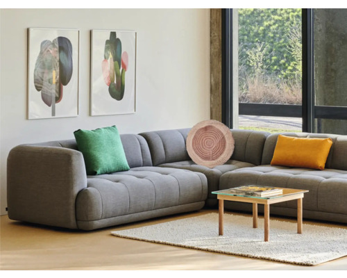 Woonkamer met grijze hoekbank, sierkussens, salontafel en kunst aan de muur