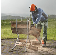 Een persoon zaagt met een kettingzaag hout op een zaagbok in de buitenlucht.