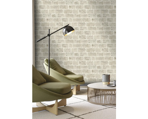 Woonkamer met bakstenen behangpatroon, fauteuils, vloerlamp en salontafel