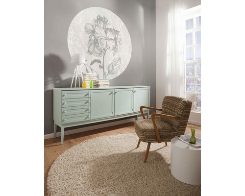 Woonkamer met dressoir, fauteuil, tapijt en wanddecoratie met bloemmotief