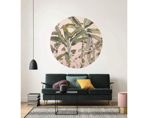 Woonkamer met groene bank, tapijt en wanddecoratie met plantenmotief