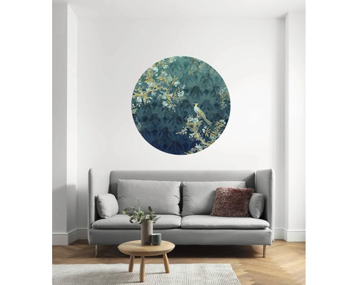 Woonkamer met ronde wanddecoratie met vogelmotief boven een grijze bank.