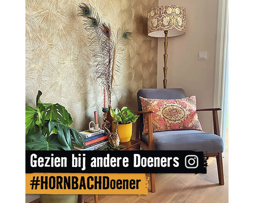 Woonkamerscène met fauteuil, vloerlamp, kamerplanten en decoratieve elementen op een bijzettafel voor een patroonbehang.