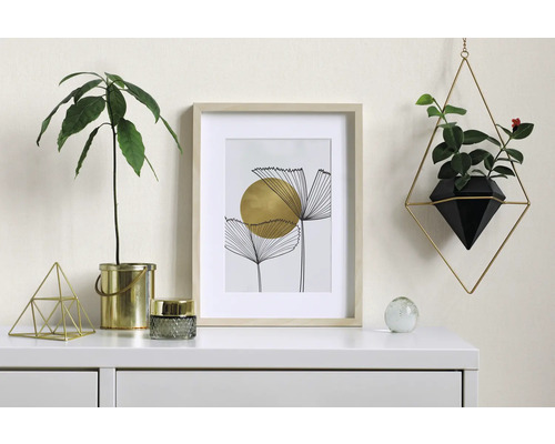 Decoratief interieur met fotolijst, planten en geometrische objecten op een witte ladekast.