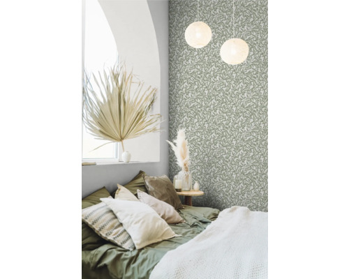 Slaapkamer met bed, decoratief behang met bladmotief en ronde hanglampen.