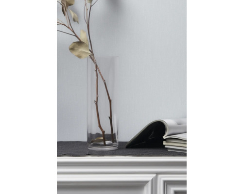 Decoratieve takken in glazen vaas naast tijdschriften op dressoir