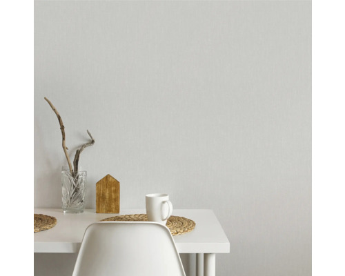 Decoratief arrangement op een witte tafel met glazen vaas, houten huis, mok en placemats