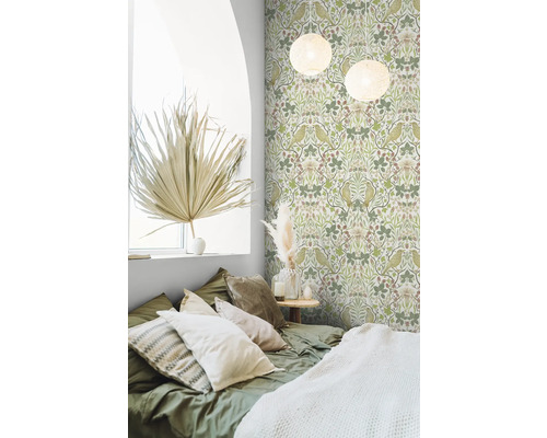 Slaapkamer met groen behang met vogel- en plantenmotief, bed met kussens en decoratieve elementen