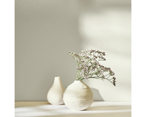 Twee witte vazen, waarvan één met droogbloemen, op een lichte achtergrond.