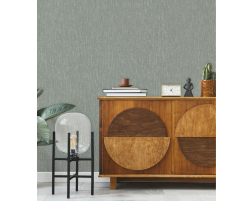 Woonkamer met patroonbehang, dressoir en decoratieve elementen.