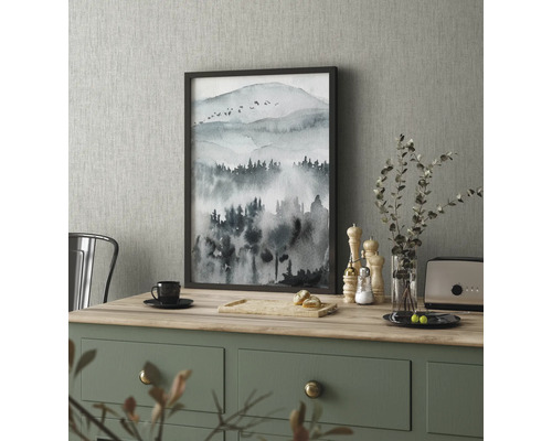 Decoratief schilderij met bergmotief in een lijst op een keukentafel.