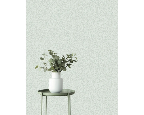 Decoratief behang met subtiel patroon en een vaas met planten op een bijzettafel.