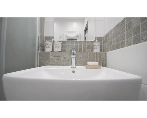 Moderne badkamer met wastafel, kraan, zeep, tandenborstelbeker en zeepdispenser