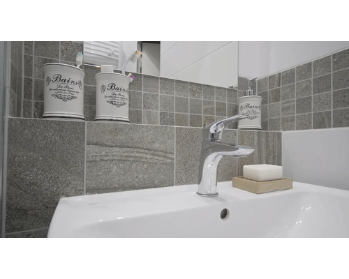 Moderne badkamer met wastafel, kraan, zeep, zeepbakje, tandenborstelbeker en dispenser