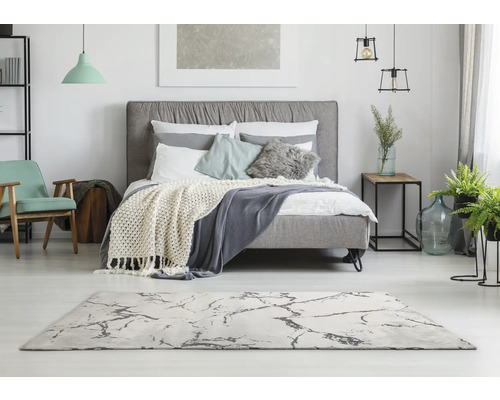 Lichte slaapkamer met bed, tapijt en decoraties voor een vriendelijke sfeer.