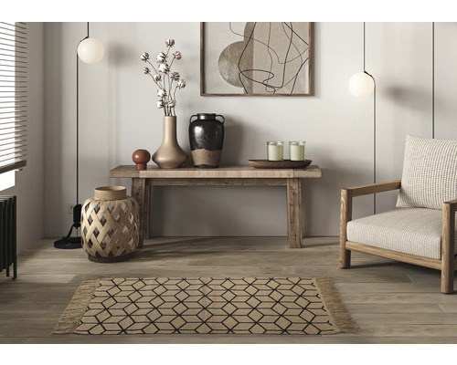 Woonkamer met vloerkleed, fauteuil, tafel en decoraties.