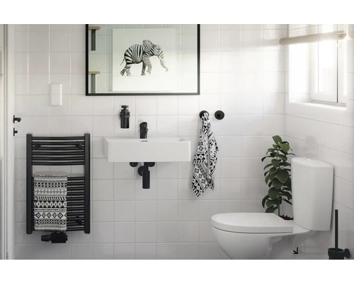 Lichte badkamer met wastafel, handdoekradiator en toilet.
