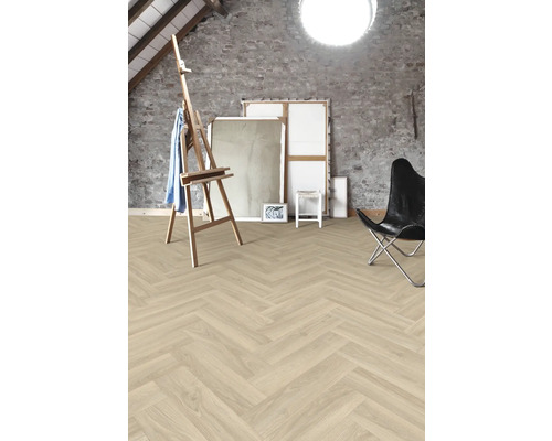 Lichte ruimte met visgraatparketvloer, schildersezel, doeken en stoel.