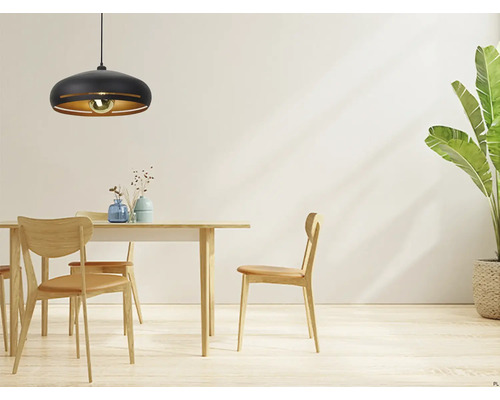 Metalen hanglamp boven eettafel met stoelen en kamerplant